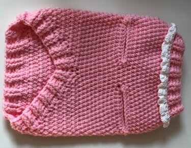 Rosa gehäkelter Hundepullover mit Rippenkragen und weißer Rüsche, flach liegend