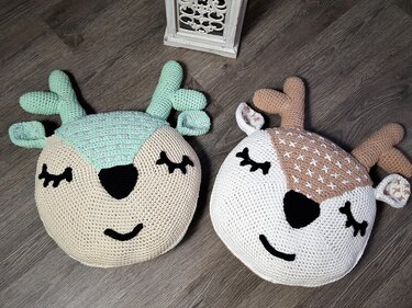 Nahaufnahme zweier gehäkelter Rentier-Kissen mit verschiedenen Stichmustern und Geweihen