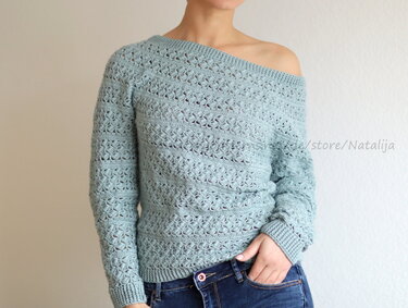 Frau trägt hellmintfarbenen, gehäkelten Off-Shoulder-Pullover mit Lochmuster und gerippten Bündchen