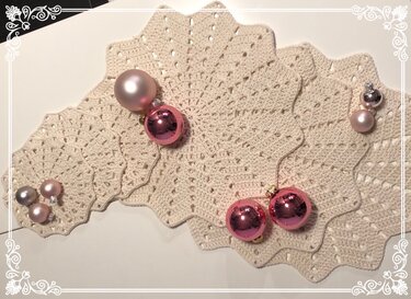 Mehrere sternförmige Häkeluntersetzer mit gezacktem Rand und Deko-Kugeln