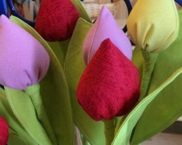 Nahaufnahme genähter Stofftulpen mit sichtbaren Nähten und grünen Blättern