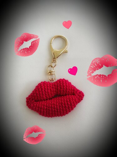 Roter gehäkelter Lippen‑Schlüsselanhänger mit goldfarbenem Karabiner auf hellem Untergrund