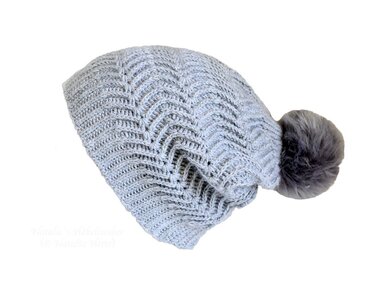 Hellgraue gehäkelte Beanie mit Zickzackmuster und dunklem Bommel auf weißem Hintergrund