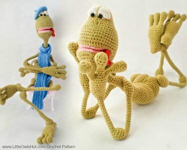 Two crocheted amigurumi creatures with long thin limbs, rounded bodies and stitched mouths on a white background