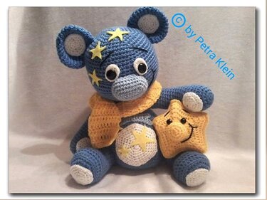 Gehäkelter blauer Amigurumi-Teddybär mit gelbem Schal und Sternkissen