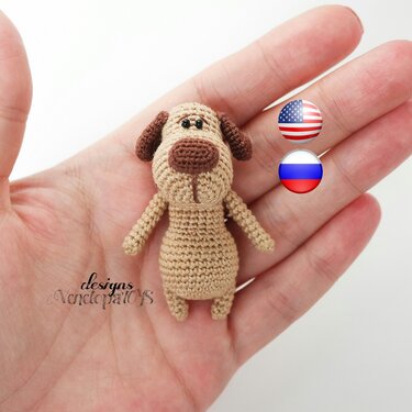 Small beige and brown crocheted amigurumi dog with floppy ears held in a hand
