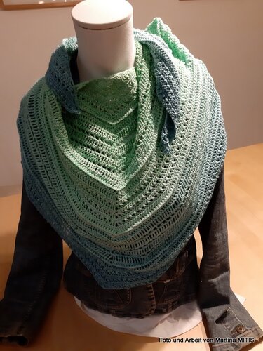 Dreieckstuch mit Grün‑Blau‑Farbverlauf und offenem Häkelmuster, drapiert auf einer Schaufensterpuppe über einer Jeansjacke