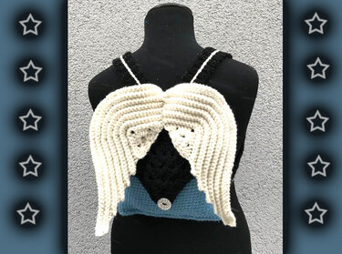 Verspielter Häkelrucksack mit markanten Flügelklappen und rundem Knopf, präsentiert auf einer schwarzen Schaufensterpuppe.