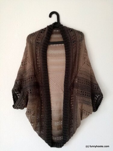 Gehäkelter Seelenwärmer in Beige‑Braun‑Farbverlauf mit Lochmuster, an einem Kleiderbügel vor weißer Wand.