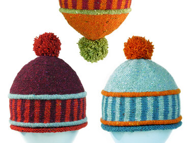 Drei gestrickte Wollmützen mit Bommel in Lila, Rot, Türkis, Hellblau und Orange, teilweise gestreift, vor weißem Hintergrund.