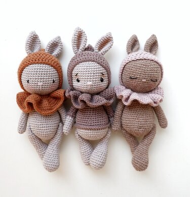 Drei gehäkelte Amigurumi-Hasen nebeneinander mit Rüschenkragen