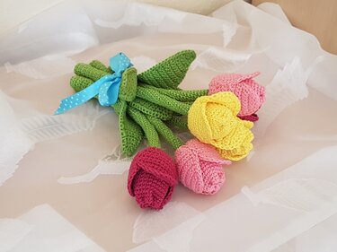 Gehäkelter Tulpenstrauß in Gelb, Rosa und Dunkelrosa mit grünen Stielen und blauem Band