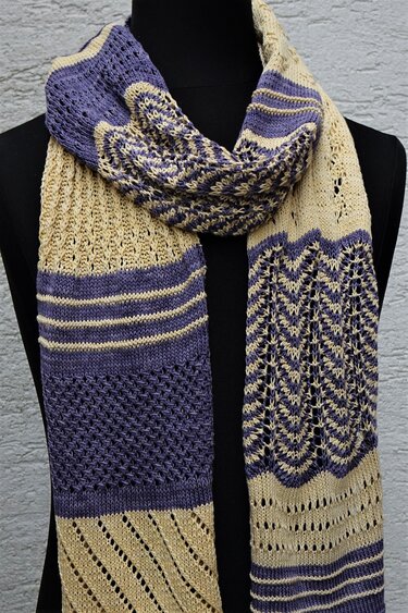 Zweifarbiger gestrickter Schal in Beige und Violett mit verschiedenen Loch- und Zickzackmustern auf schwarzer Schneiderpuppe.