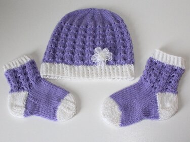 Gestricktes Baby-Set: lila Mütze mit weißem Bund und passende Socken, Lochmuster, Blütenapplikation