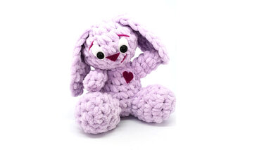 Fliederfarbener gehäkelter Amigurumi-Hase mit Schlappohren und Herzapplikation