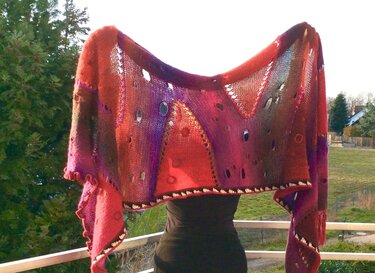 Mehrfarbiges gestricktes Rechtecktuch mit Ajour‑Lochmuster und Farbverlauf, im Freien präsentiert