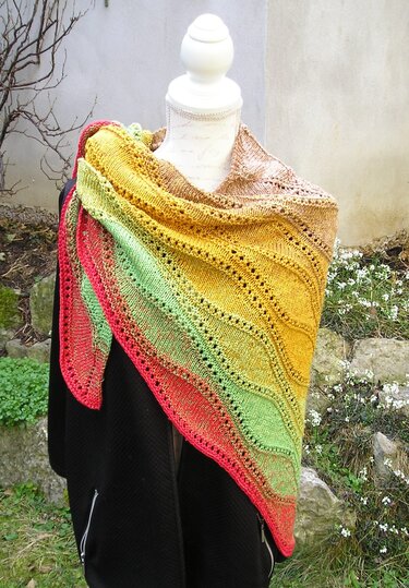 Gestricktes Dreieckstuch auf Schneiderpuppe mit Farbverlauf (Rot–Grün–Gelb–Braun) und Ajourmuster.