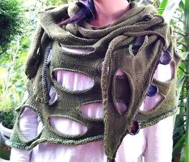 Olivgrünes asymmetrisches Stricktuch mit ovalen Öffnungen über weißem Shirt