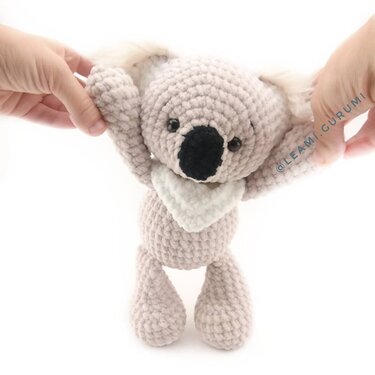 Gehäkelter Koala Amigurumi mit Halstuch, gehalten von zwei Händen