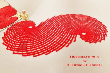 Red crocheted table runner with an S-shaped wavy open lace pattern on a light surface.