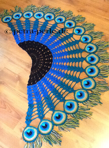 Semicircular crochet shawl with peacock-eye motifs, lacy fan stitches and green-blue fringe