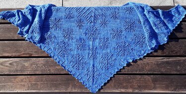 Gestricktes blaues Dreieckstuch mit filigranem Ajourmuster auf Holz