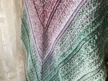 Nahaufnahme eines gehäkelten Dreieckstuchs zeigt Musterstruktur und Farbübergang