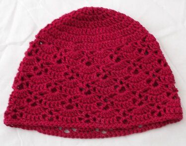 Gehäkelte Kinder-Mütze in dunkelpink mit einfachem Muschelmuster, flach liegend