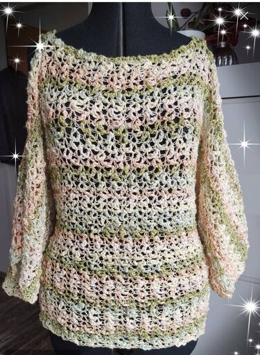 Gehäkelter Damenpullover mit Lochmuster in Pastellfarben auf schwarzer Schneiderpuppe