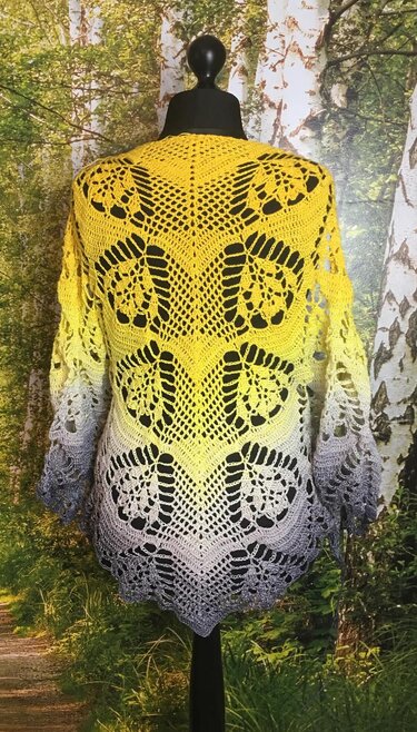 Back view of a yellow-to-gray ombre crocheted triangle shawl with lace motifs on a black mannequin.