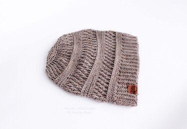 Textured crochet slouchy beanie in brown-gray melange yarn laid flat on a white background.