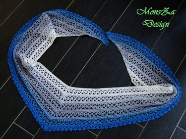 Blau-weißes gehäkeltes Dreieckstuch mit Lochmuster und Zierkante auf dunklem Boden