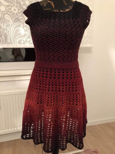 Gehäkeltes Kleid mit Farbverlauf von Dunkelrot zu Orange auf Schneiderpuppe, taillierter Bund und luftige Lochmuster