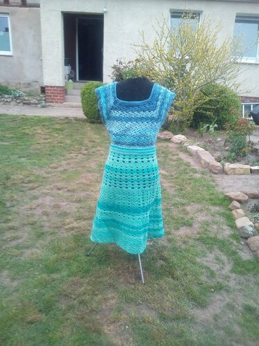 Gehäkeltes Kleid in Blau- und Türkistönen auf schwarzer Schneiderpuppe im Garten