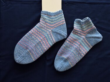 Paar knöchelhoher gestrickter Damensocken in pastelligen Blau-, Rosa- und Grüntönen mit feinen Streifen auf dunkelblauem Hintergrund