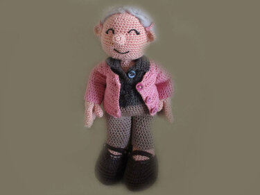 Gehäkelte Amigurumi-Puppe mit rosa Jacke, Knöpfen und dunklen Schuhen