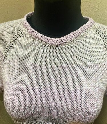 Kurzärmeliger melierter Damen-Strickpullover mit lila Halsausschnittborte auf einer schwarzen Schaufensterpuppe.