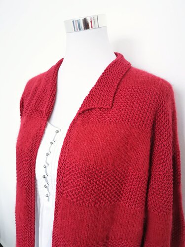 Rote Damenstrickjacke mit Streifen aus glattem und texturiertem Strick an einer Schaufensterpuppe