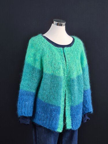Flauschige, gestreifte Strickjacke in Blau-, Türkis- und Grüntönen an einem Mannequin