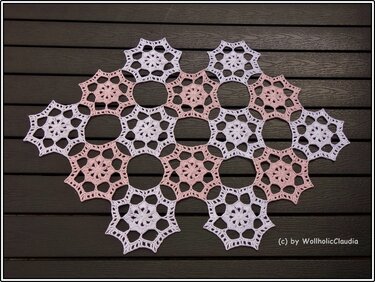 Rosa-weiße sternförmige gehäkelte Granny-Motive auf dunklem Holz