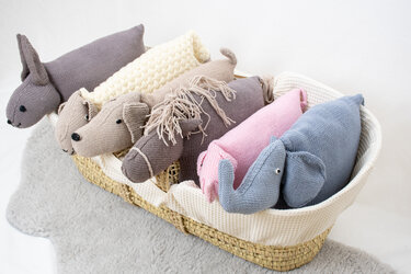 Verschiedene gestrickte Tierkissen nebeneinander in einem Korb