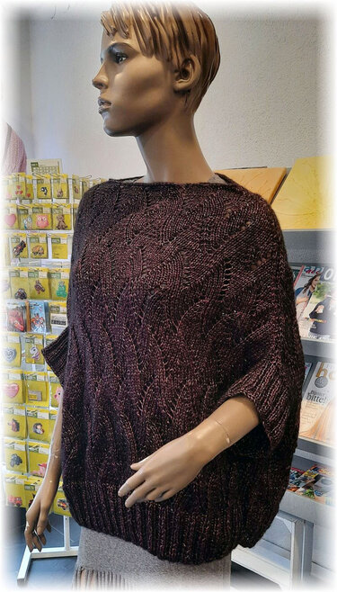 Dunkelroter gestrickter Damenponcho mit Zopfmuster auf Schaufensterpuppe.