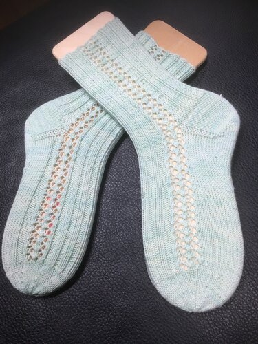 Handgestrickte mintgrüne Damensocken mit Ajour-Lochmuster auf Sockenspannern.