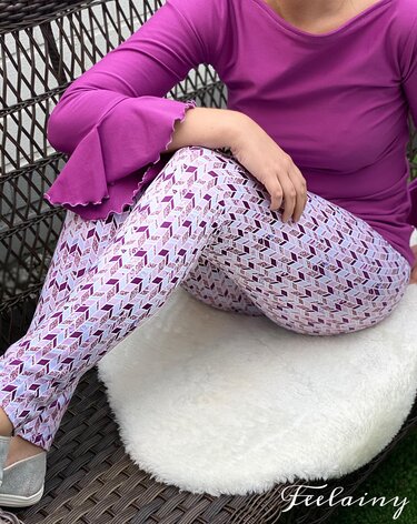 Person trägt lila Langarmshirt mit Rüschenärmeln und Leggings mit 3D-Würfelmuster