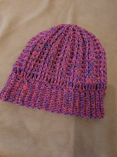 Gehäkelte Beanie in Pink und Lila mit Rippenbund auf hellem Hintergrund