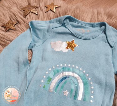 Hellblauer Babybody mit Plottermotiv aus Regenbogen, Wolke und mehreren Sternen.