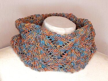 Bunter gestrickter Loopschal aus mehrfarbiger Wolle mit offenem Lochmuster auf cremefarbenem Dekomannequin.