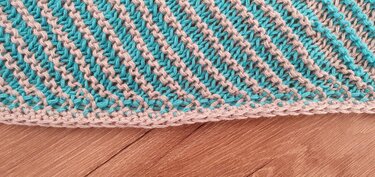 Close-up of teal and beige knit showing diagonal stitch repeat