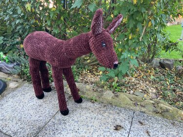 Seitenansicht eines stehenden, braunen Reh-Amigurumis mit langen Beinen und geformtem Kopf