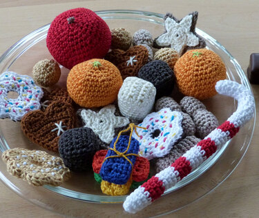 Glasschale mit gehäkelten Früchten, Plätzchen, Donut und rot-weiß gestreifter Zuckerstange